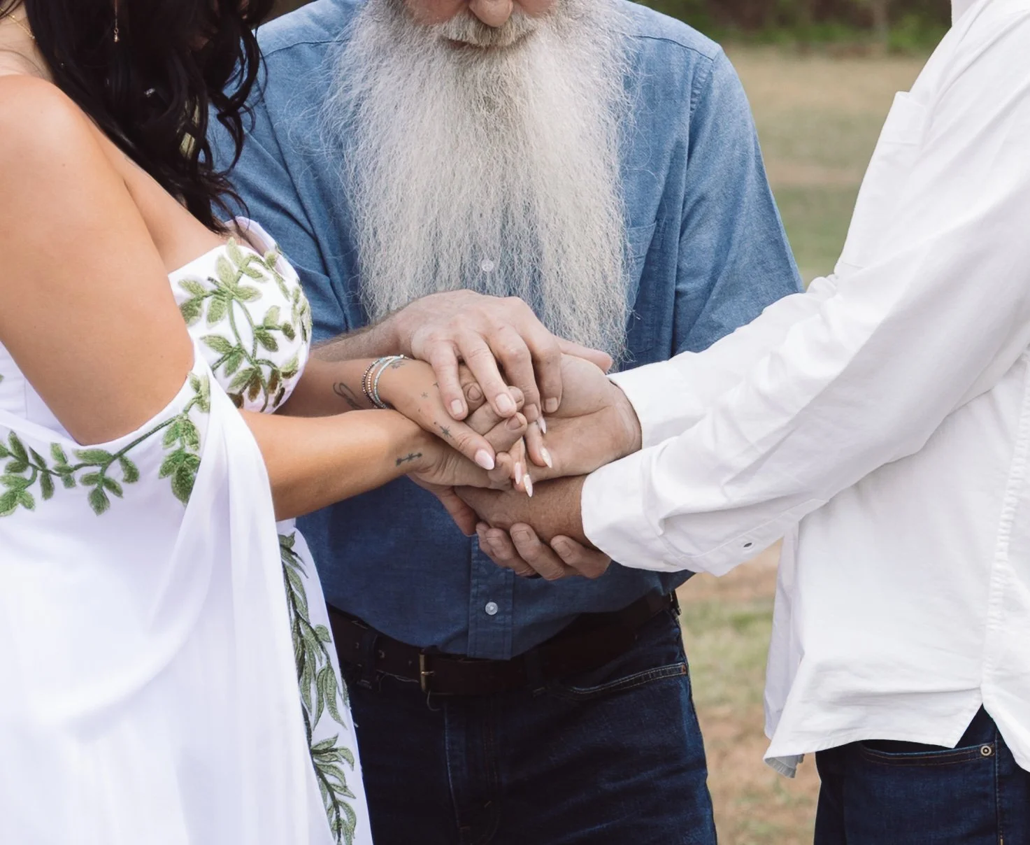 A diverse group of people holding hands in a circle during a ceremony outside.