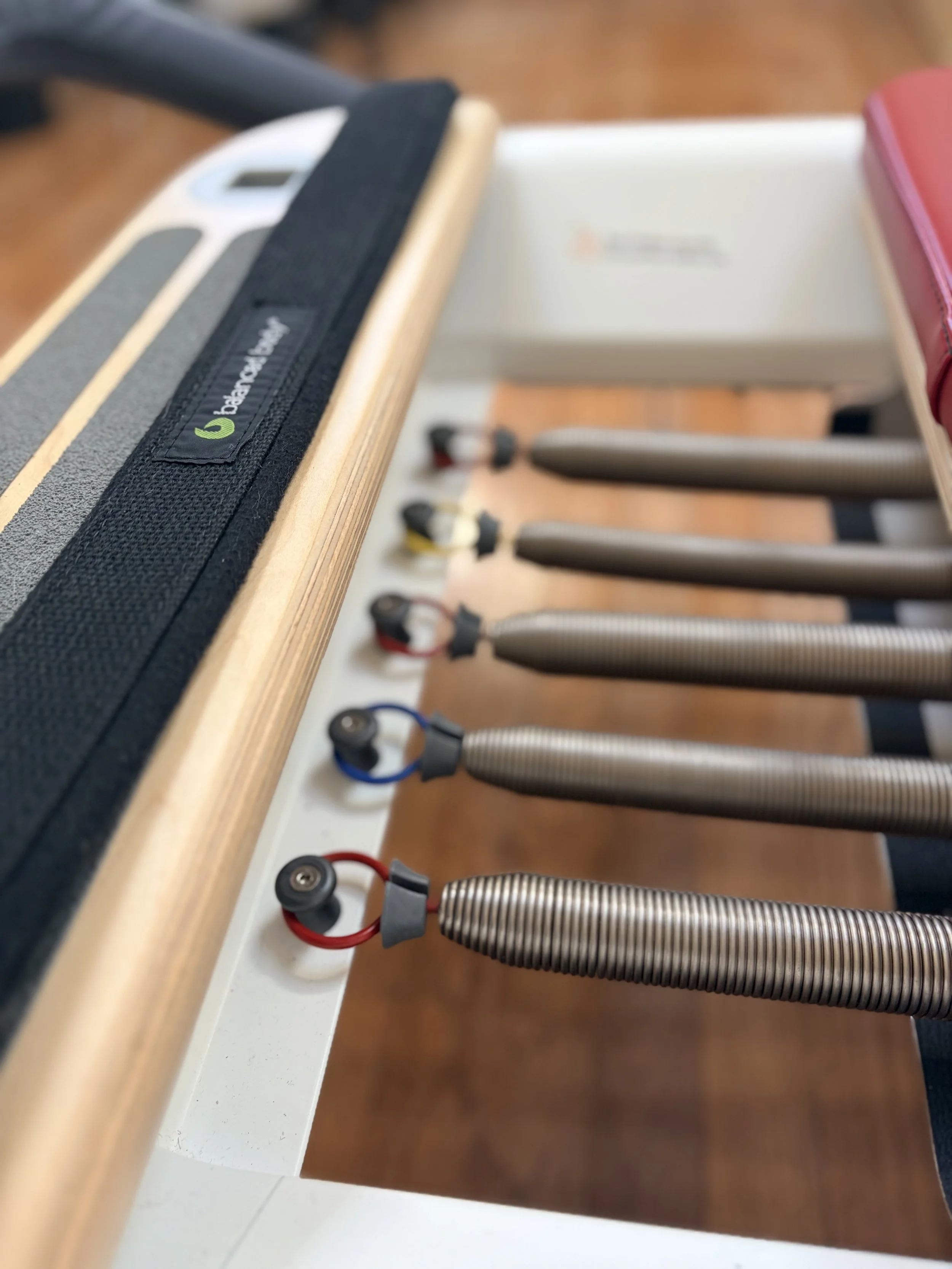 Close-up detail of adjustable gear bar and resistance springs on professional Pilates reformer machine.