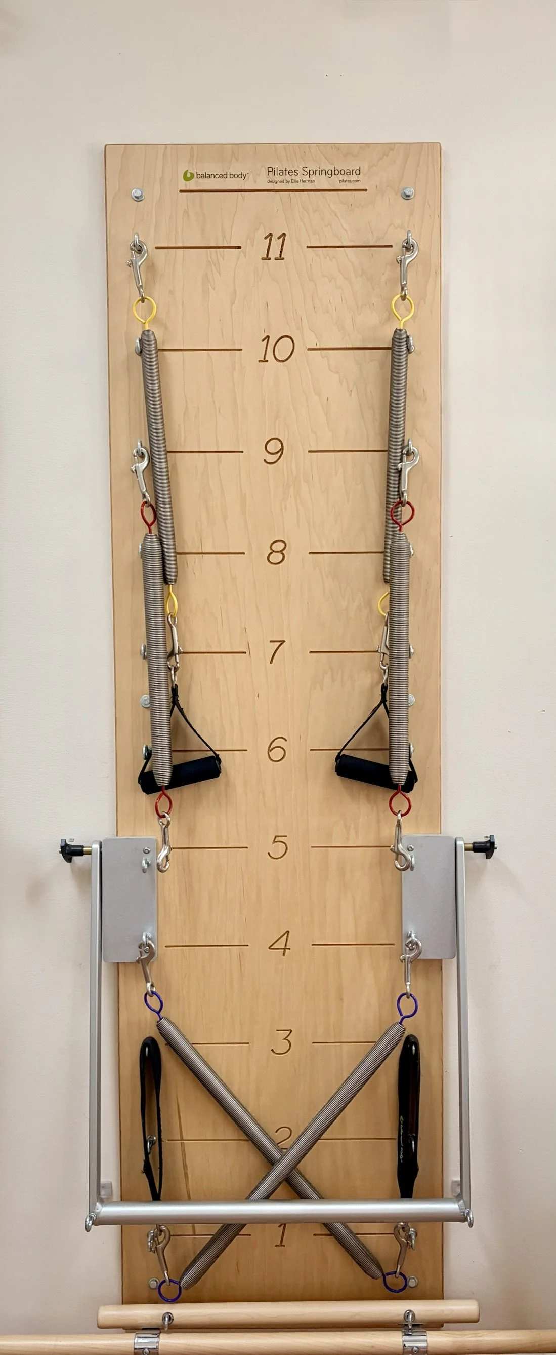 A wall-mounted Pilates Springboard with resistance springs used for private exercise sessions.