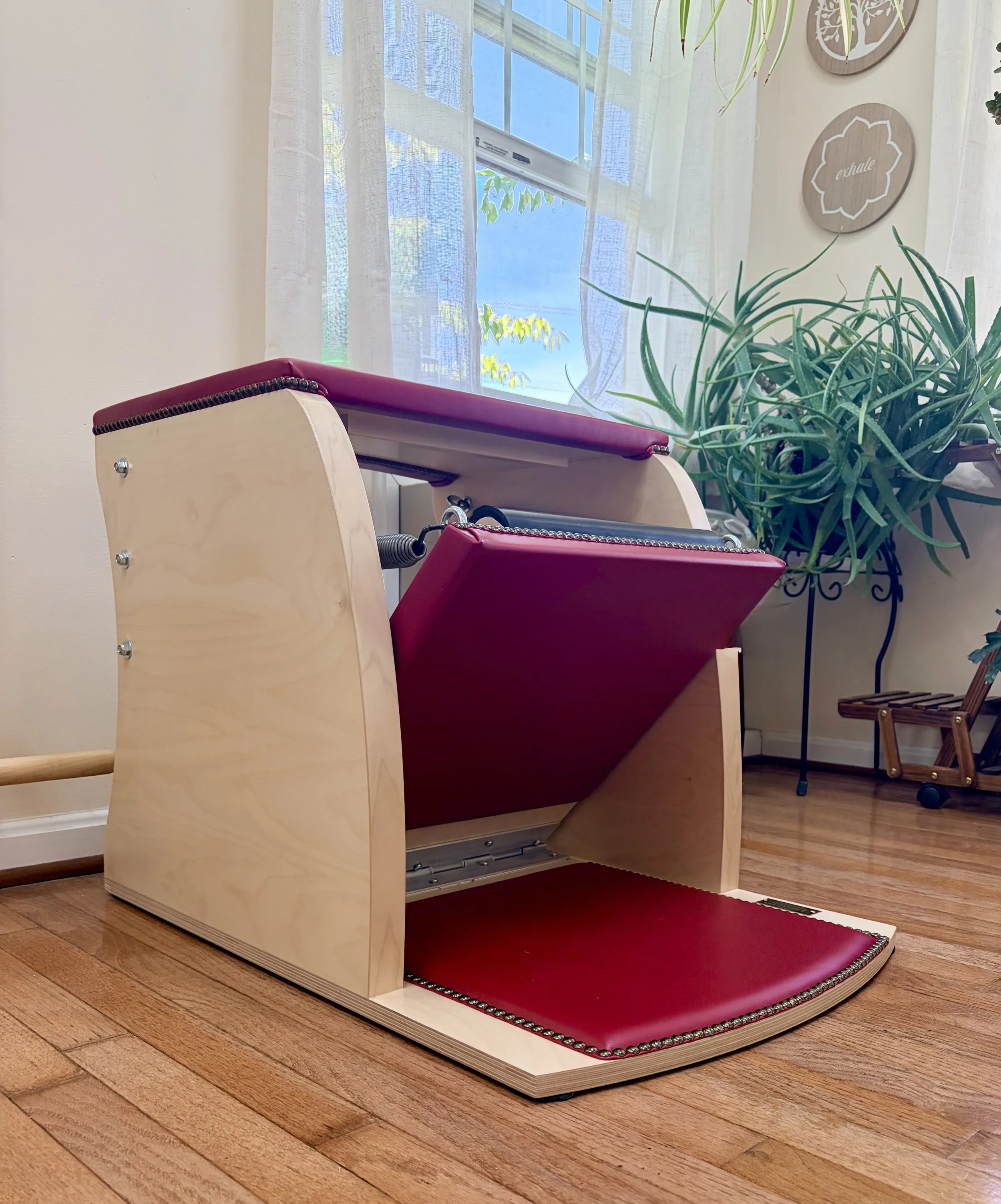 A professional wooden Pilates combo chair apparatus set up for targeted rehabilitation and strength training.