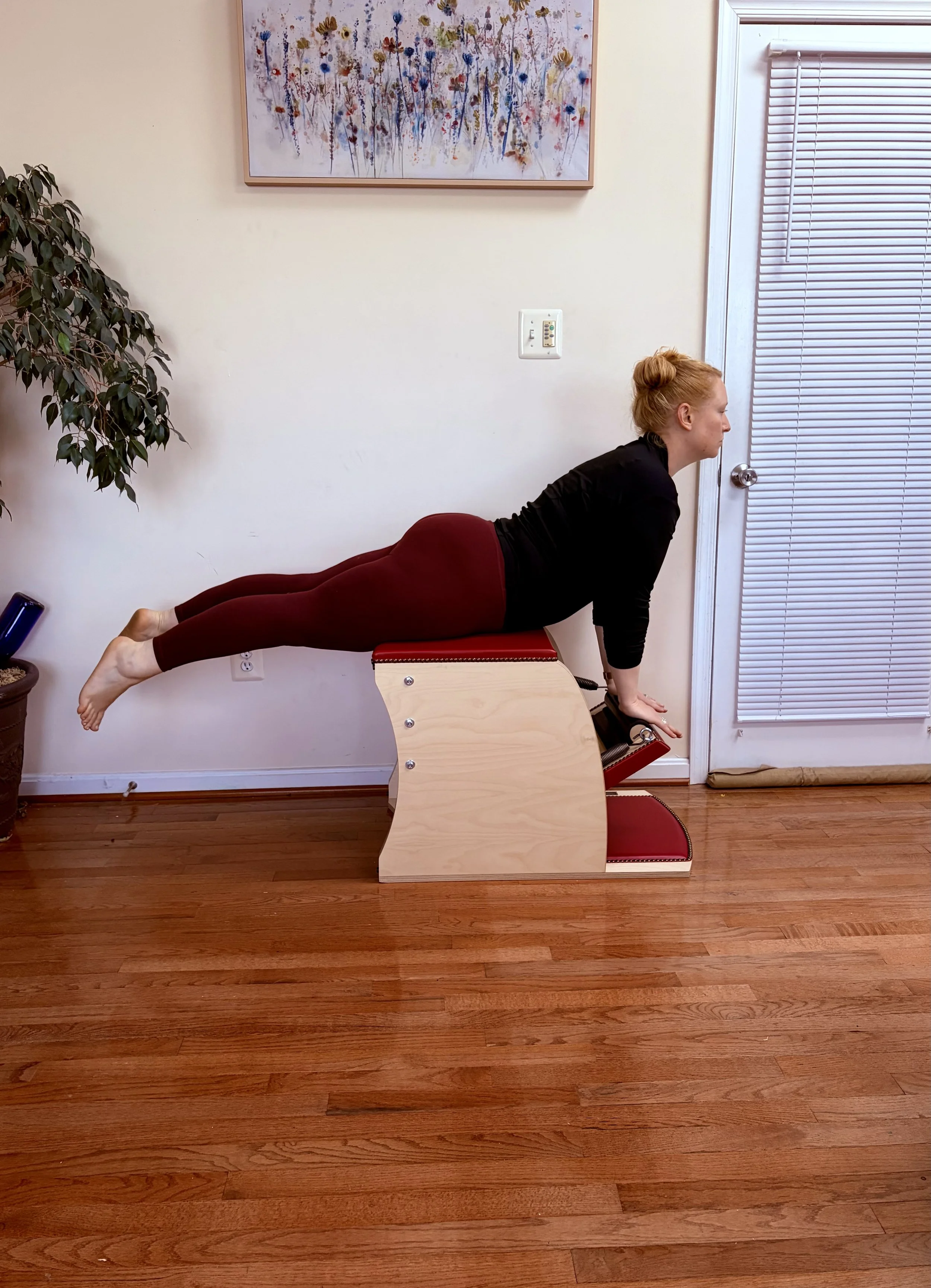 A woman performing a pilates exercise using specialized studio equipment in a private session.
