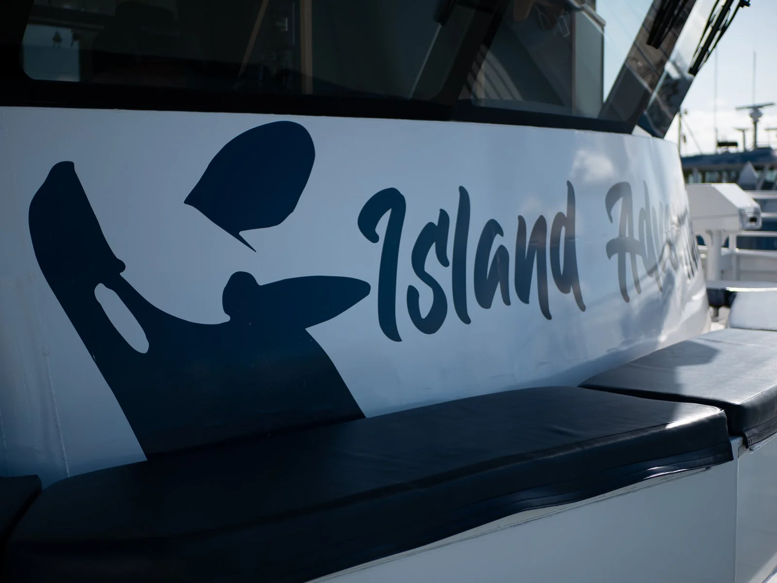 Close-up of a boat with the words 'Island AH' written on the side, and a black silhouette of a island or island shape.
