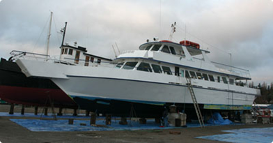 Large white and blue yacht on land with a cloudy sky background.