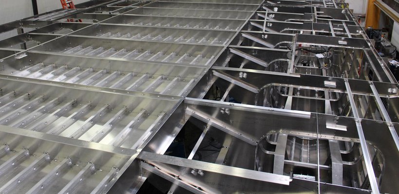 Metal framework and components of an aircraft or machinery under construction, with visible structural beams and panels.
