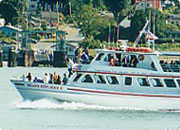 A large white boat with people on board sailing in the water.