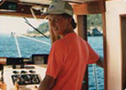 A person wearing a red shirt and cap on a boat.
