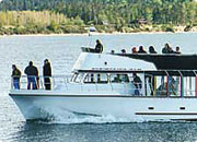 A boat on the water with people on board, and a person standing at the front.