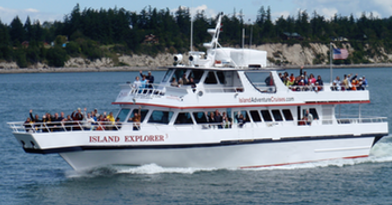 A large white passenger ferry named Island Explorer sailing on the water with passengers onboard.