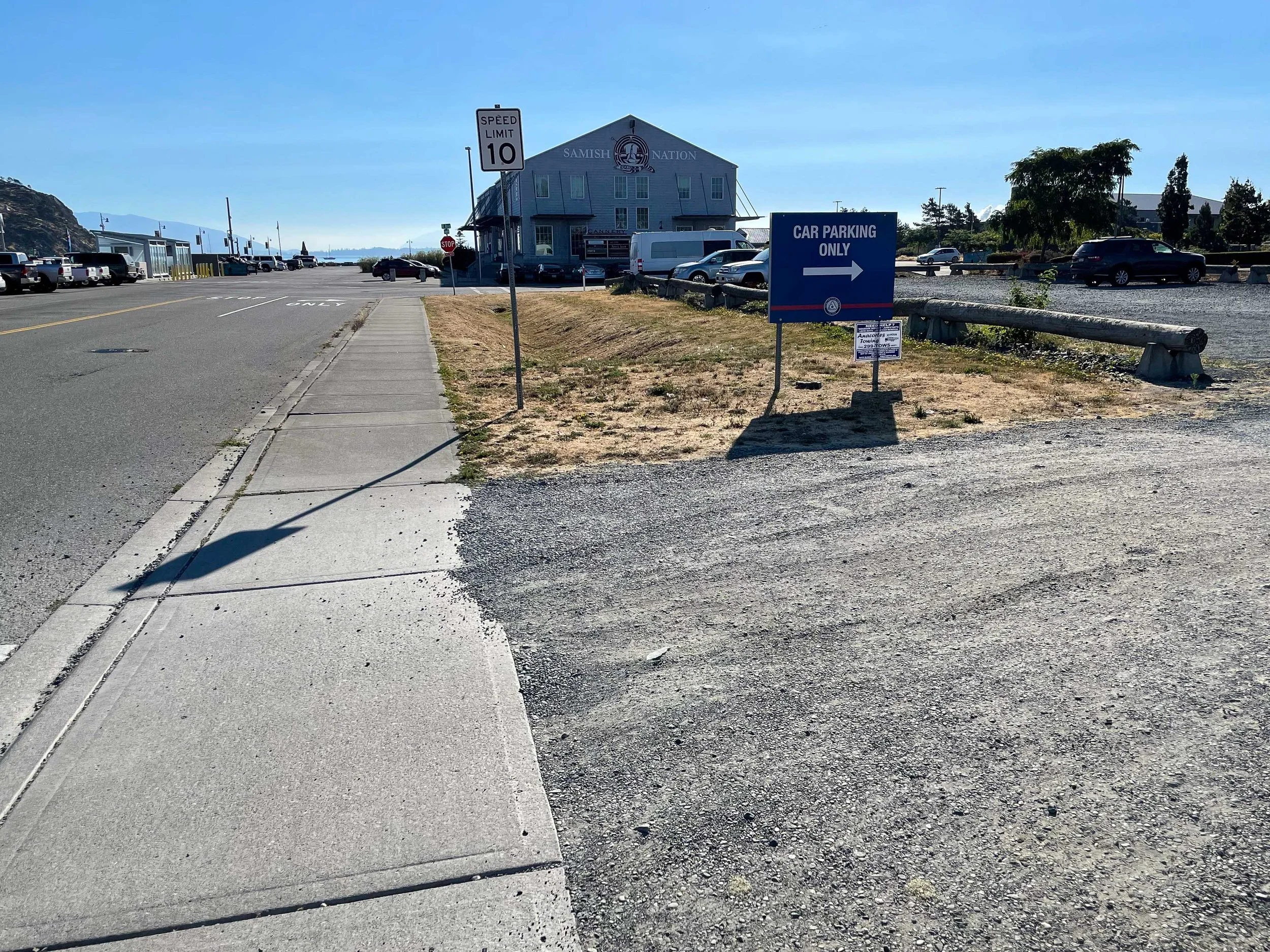 Image of a parking lot with a sign indicating 'Car Parking Only' point to the right, a speed limit sign showing 10 mph, and a building with the sign 'Samish Nation' in the background.