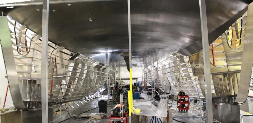 Interior of a boat under construction with metal framework and tools.