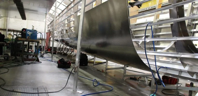 View of an aircraft fuselage under construction or repair inside a workshop, with tools and equipment around.