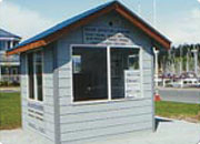 Small blue and white wooden structure resembling a shed or kiosk with a window and a gabled roof.