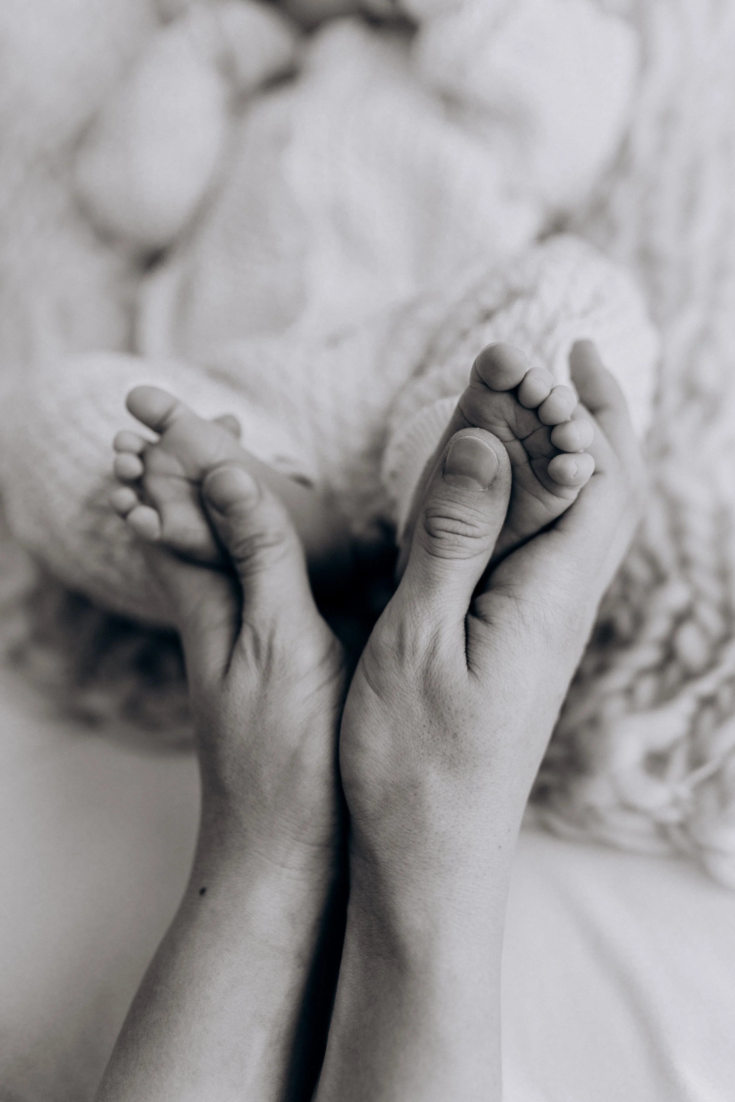 Schwarz-weiß-Fotografie eines Erwachsenen, der eine Hand eines Babys hält.