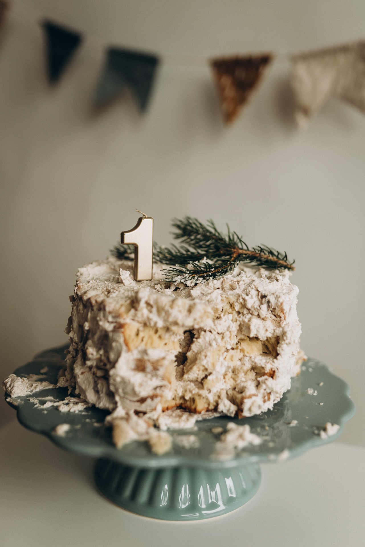 Ein Kuchen, deko mit einem Kerzenhalter mit der Nummer 1 und einem kleinen Tannenzweig, auf einer grünen Tortenplatte.