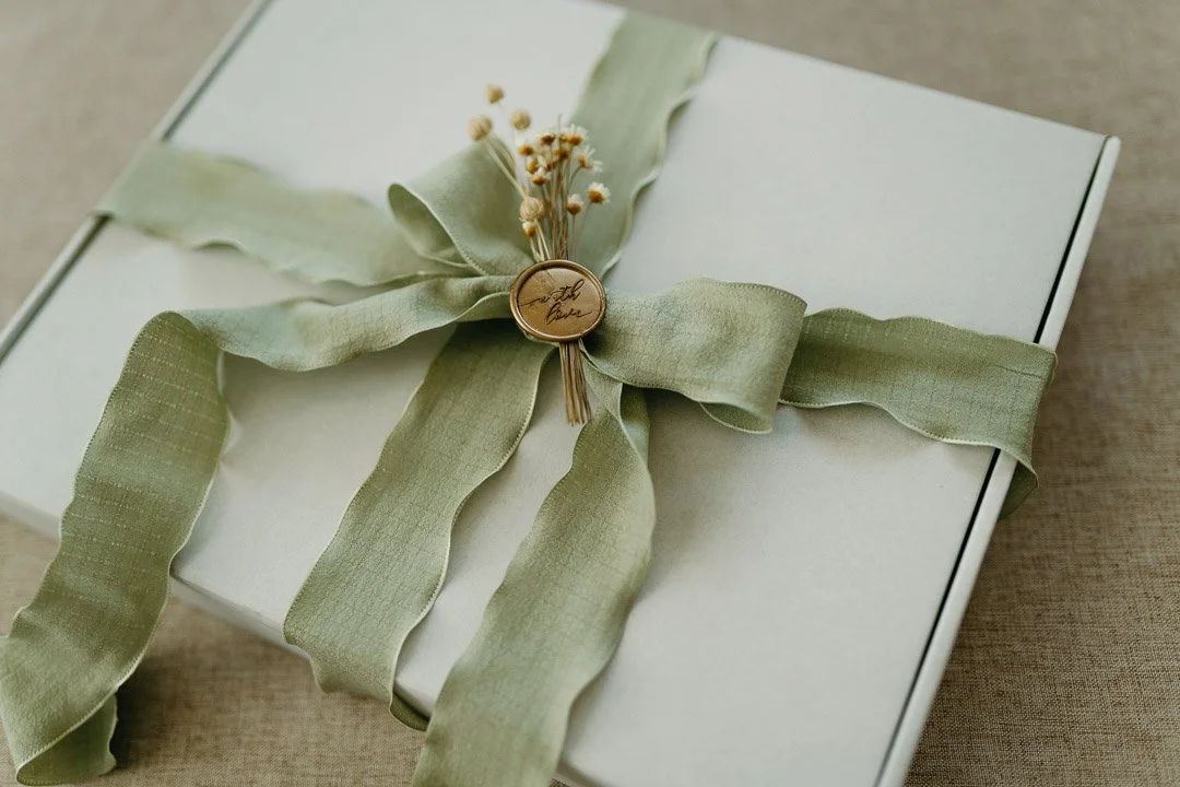 Geschenkbox mit grüner Schleife und kleiner Blumen im Verschluss