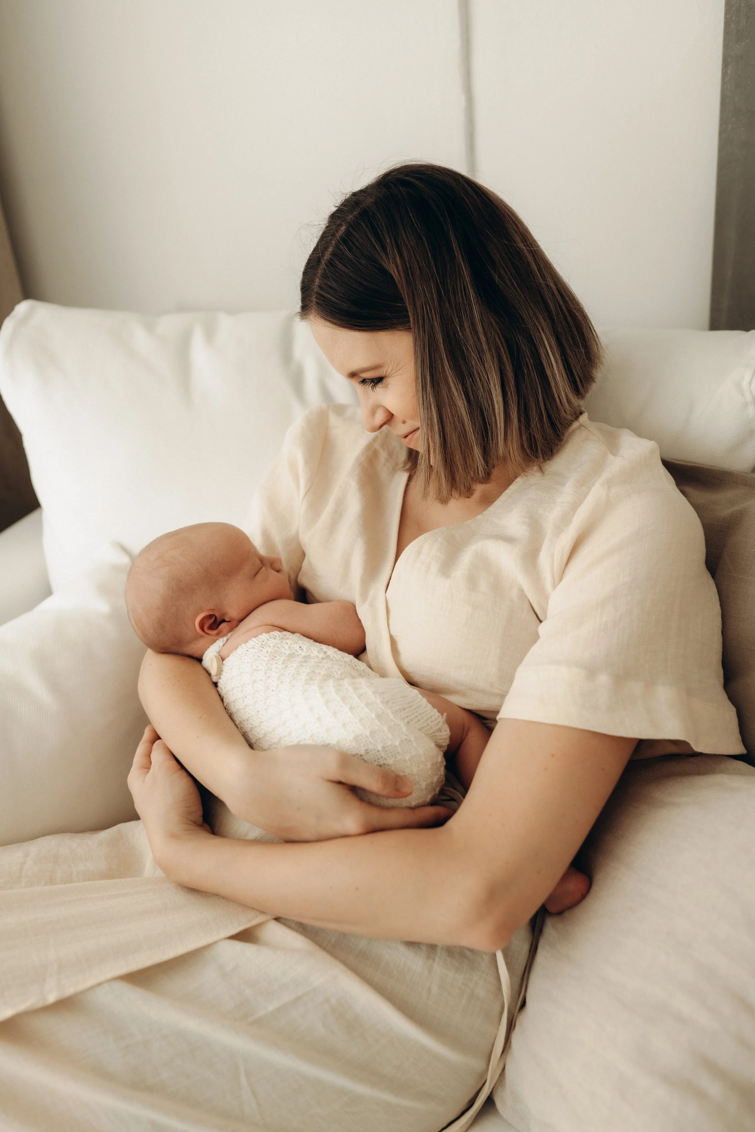 Ein Baby, das friedlich in den Armen seiner Mutter schläft, während eines Newborn-Fotoshootings in Klagenfurt, Kärnten.
