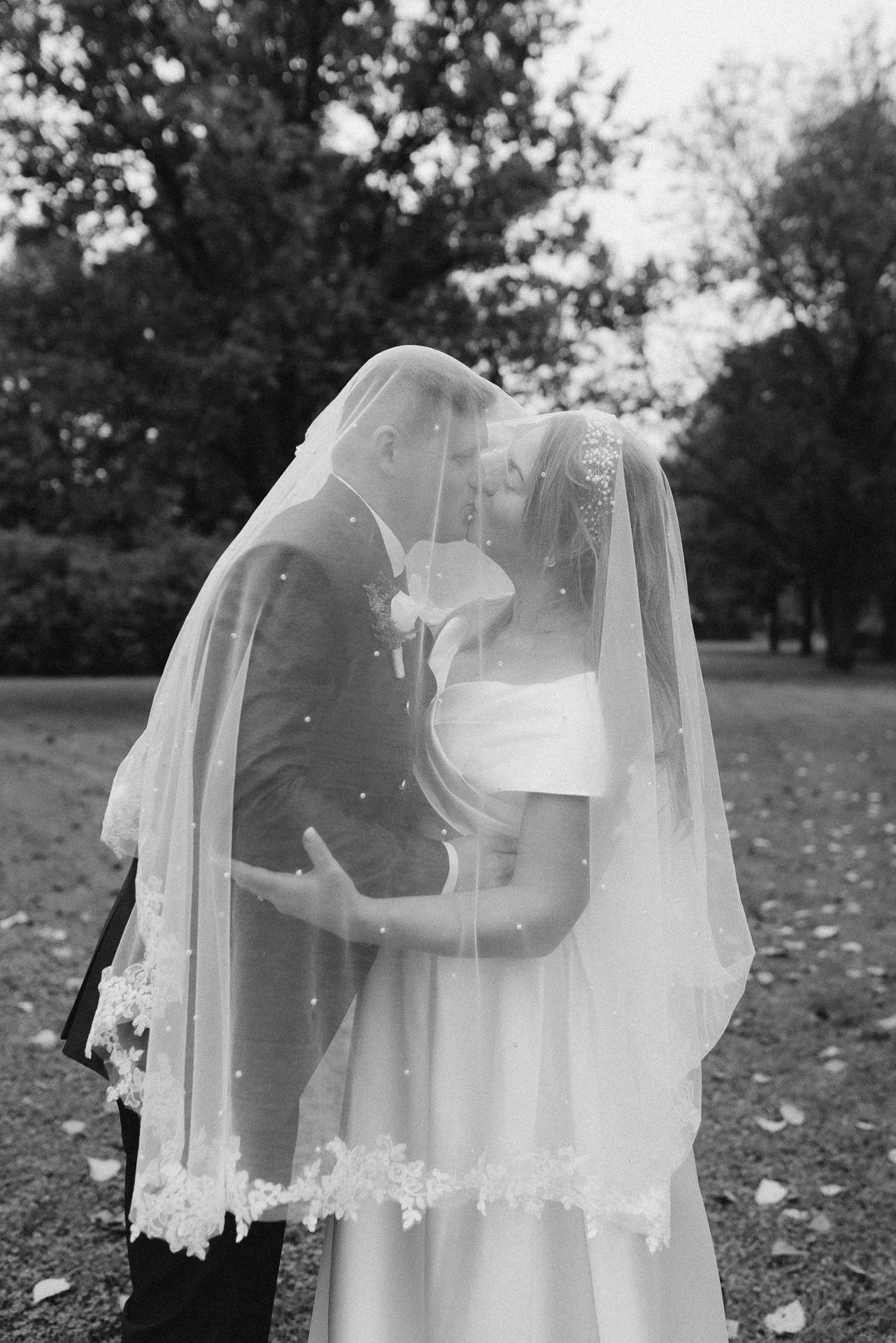 Ein Brautpaar teilt einen Kuss im Freien, die Braut trägt ein weißes Hochzeitskleid mit Schleier, der Bräutigam einen schwarzen Anzug während eines Hochzeitsfotoshootings in Kärnten.