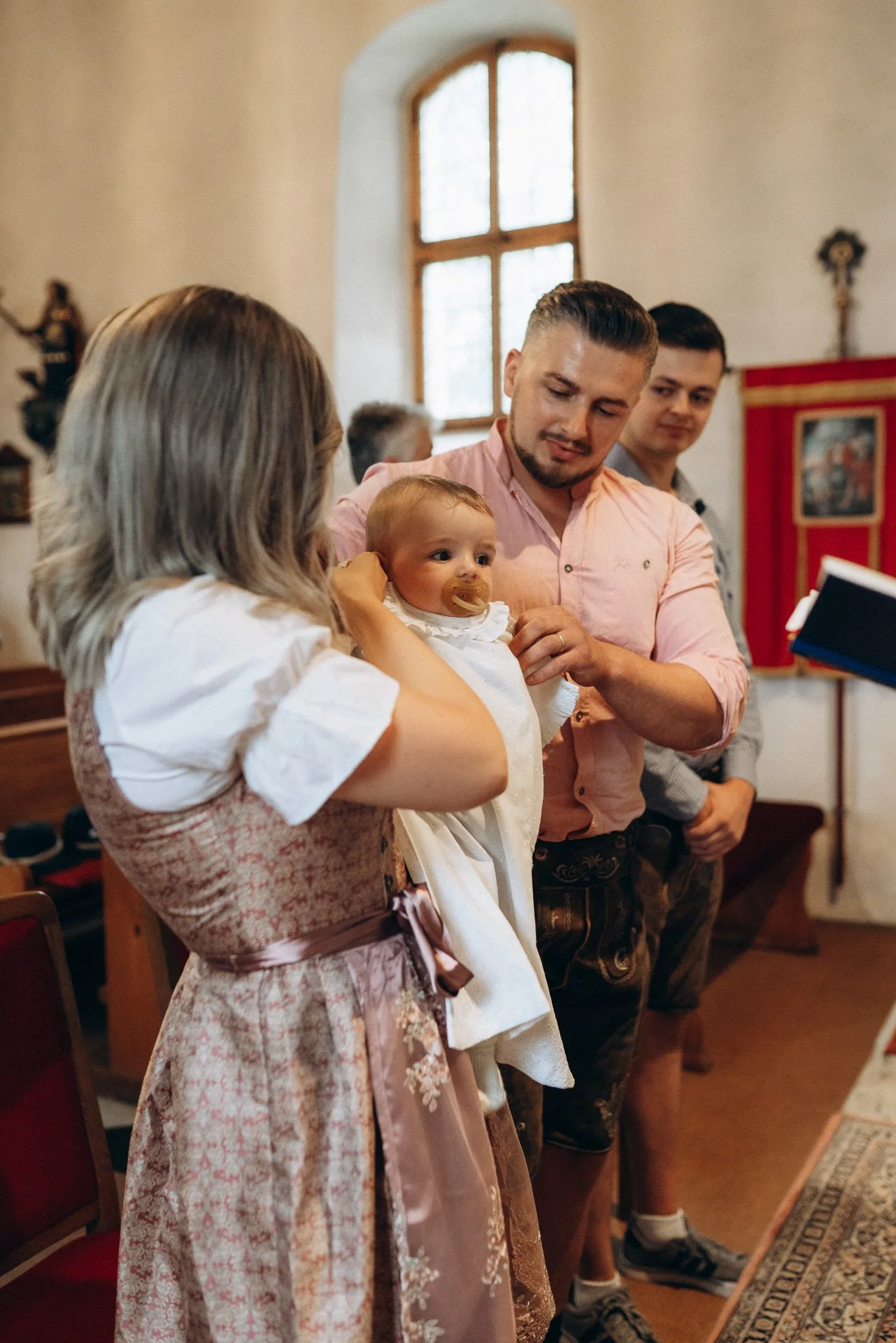 Eine Gruppe von Menschen, darunter ein Baby, in einer Kirche während einer religiösen Zeremonie.