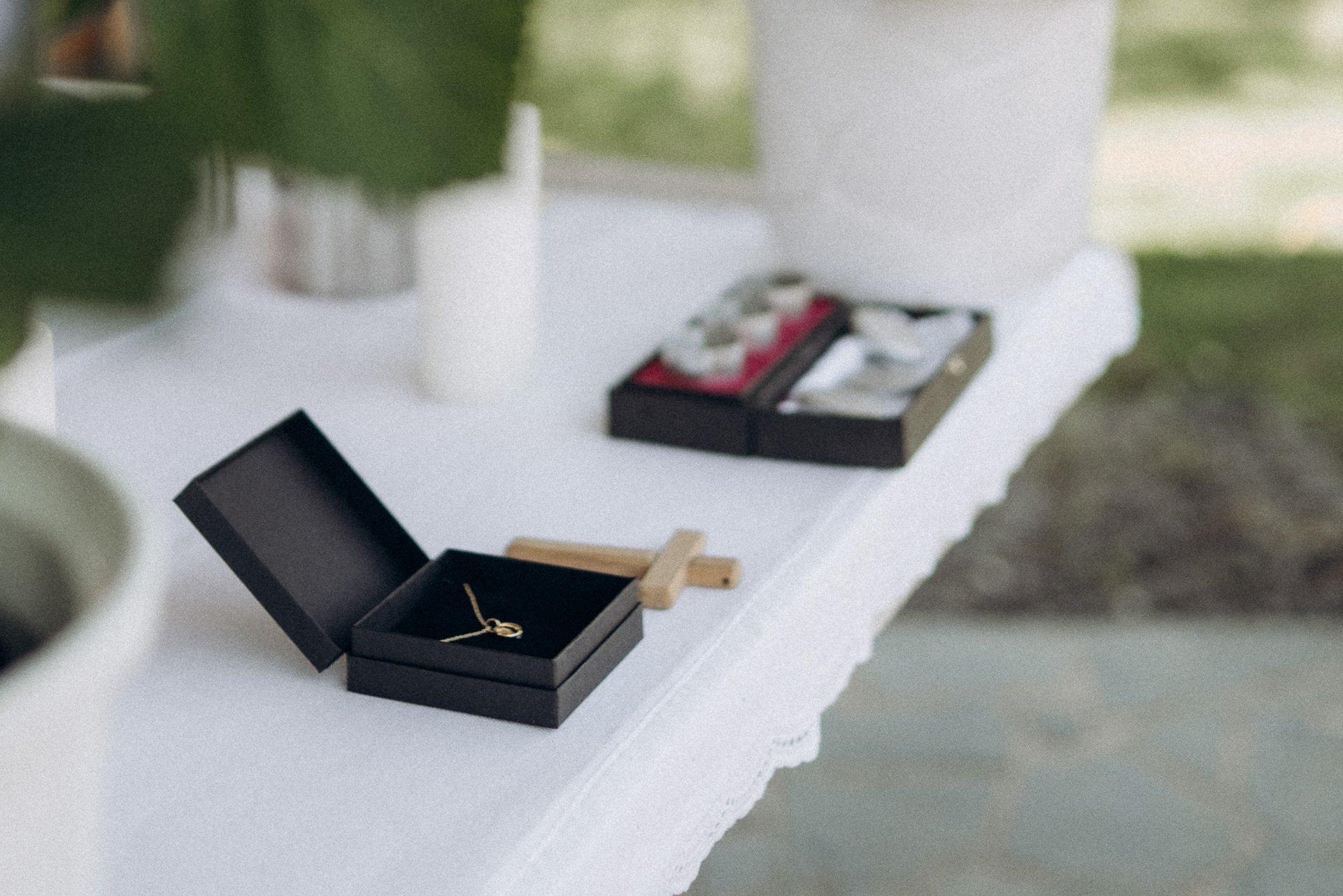 Ein Tisch mit Schmuck, Unterlagen und kleinen Schmuckkästchen, die auf einer weißen Tischdecke liegen, im Hintergrund unscharf. 