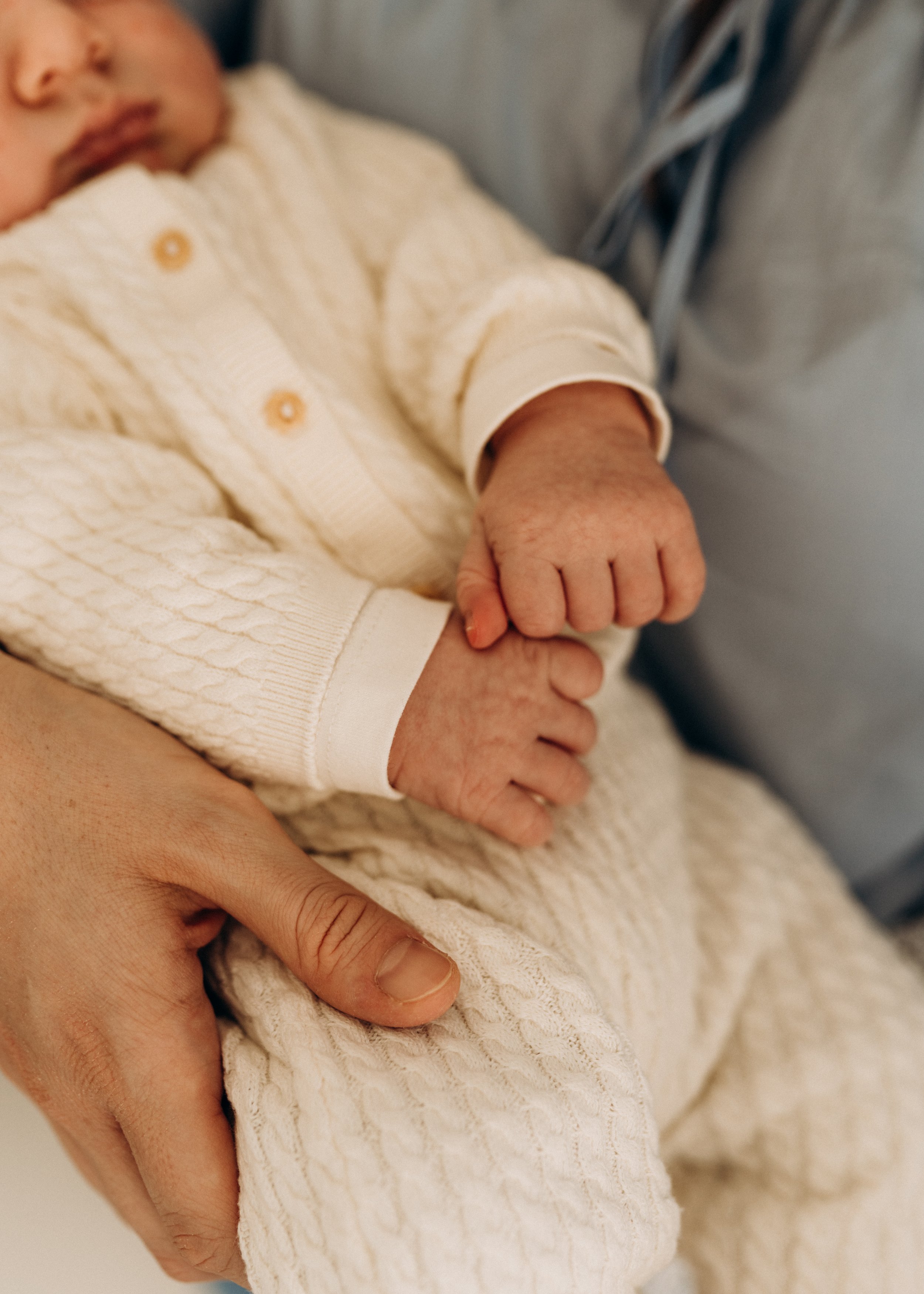 Nahaufnahme eines Babys in einem weißen, strukturierten Strampler beim Babyfotoshooting in Klagenfurt, Kärnten.