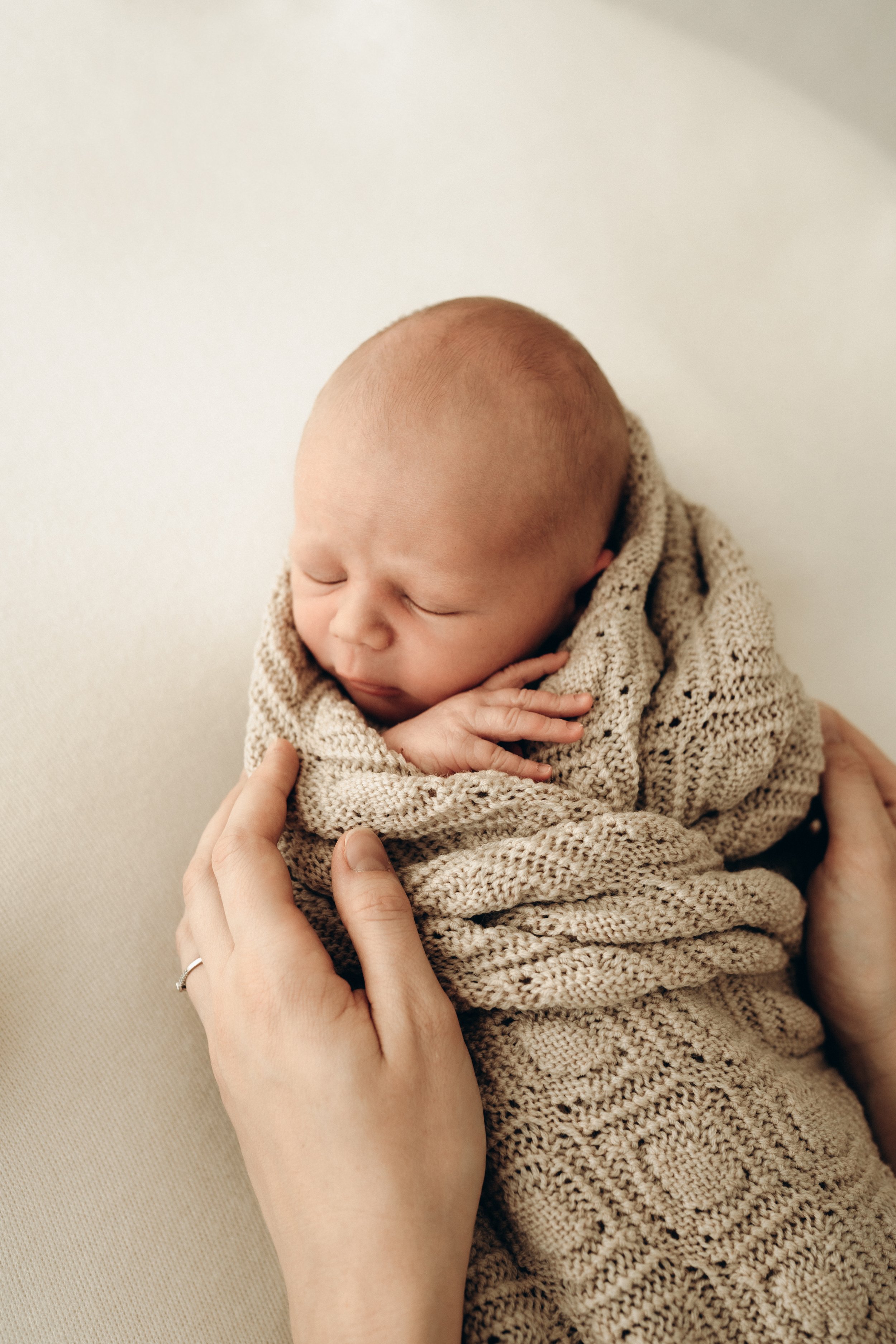 Ein schlafendes neugeborenes Baby in einem gestrickten Pullover während eines Neugeborenen-Fotoshootings in Klagenfurt, Kärnten.