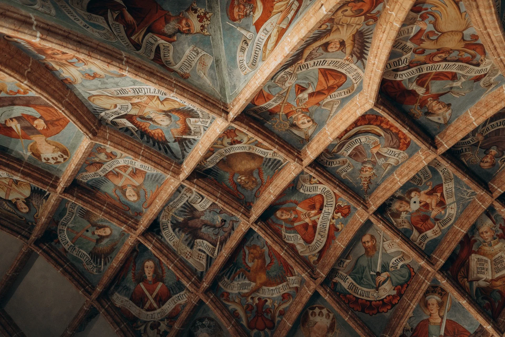 Gemälde und Szenen auf einer gewölbten Kirchendecke, mit religiösen Figuren und Texten
