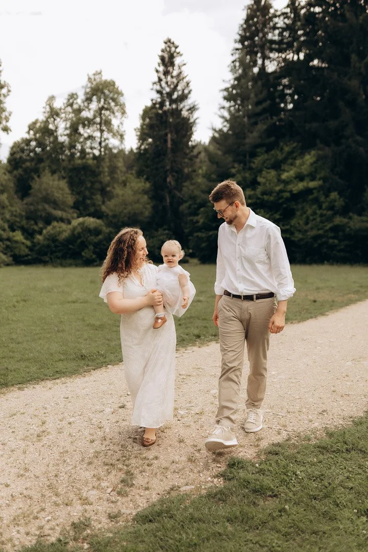 Familie mit Mutter, Vater und Baby beim Spaziergang im Park.