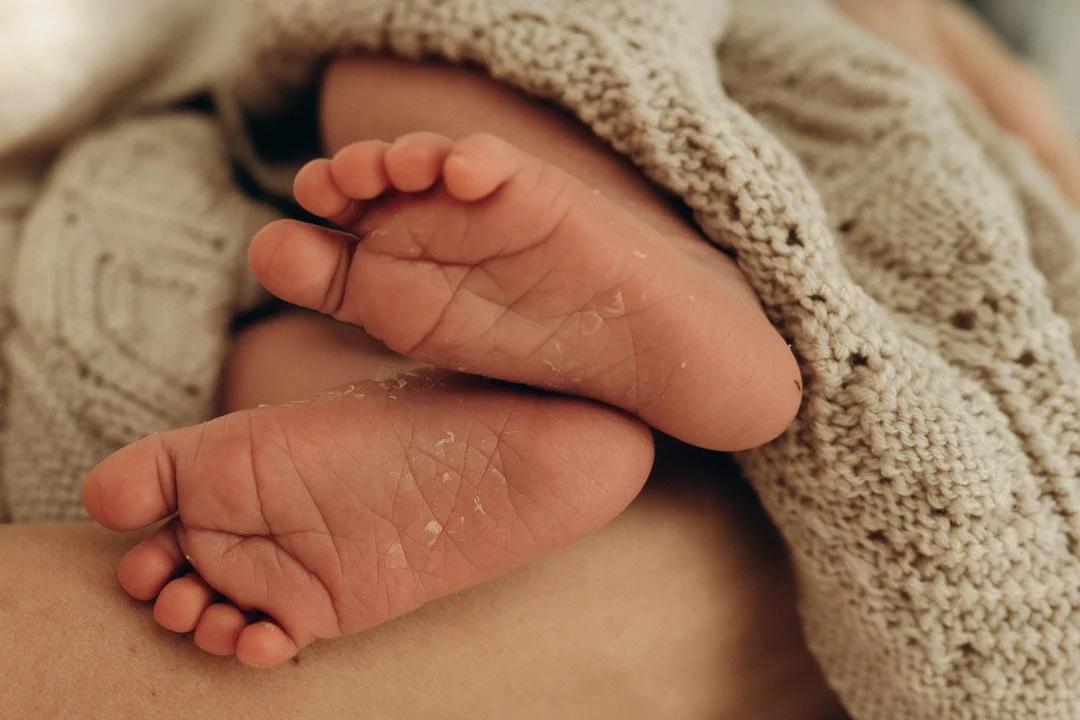 Kleine Babyfüße, eingekuschelt in eine sanfte Decke, fotografiert während eines Babyfotoshootings in Klagenfurt.