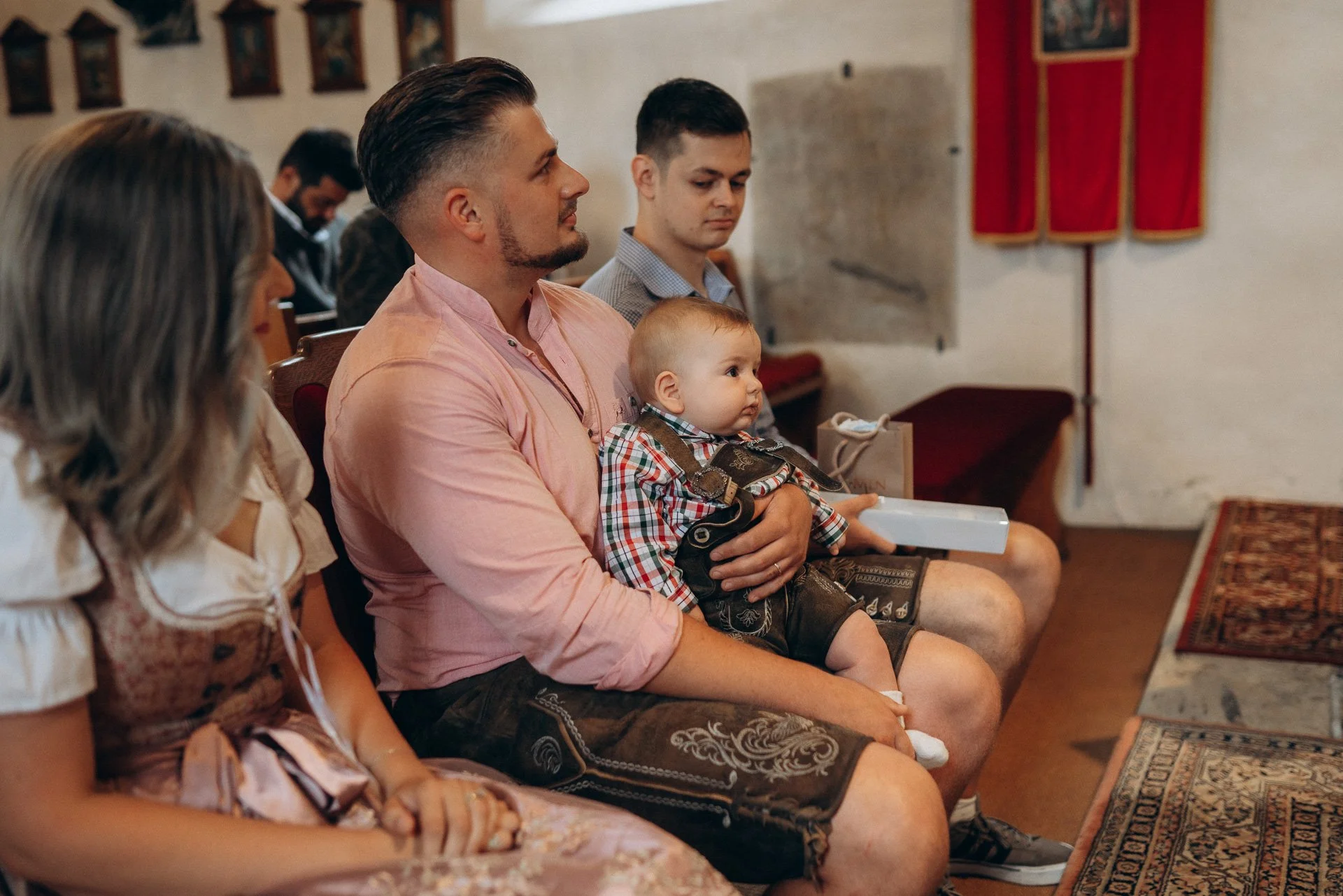 Menschen sitzen in einer Kirche während eines Gottesdienstes, darunter ein Mann mit einem kleinen Kind auf dem Schoß.