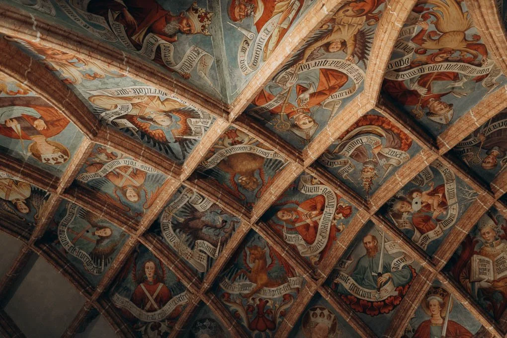 Bunte Deckenmalereien in einem Kirchengewölbe, fotografiert während einer Taufenreportage in Klagenfurt, Kärnten.