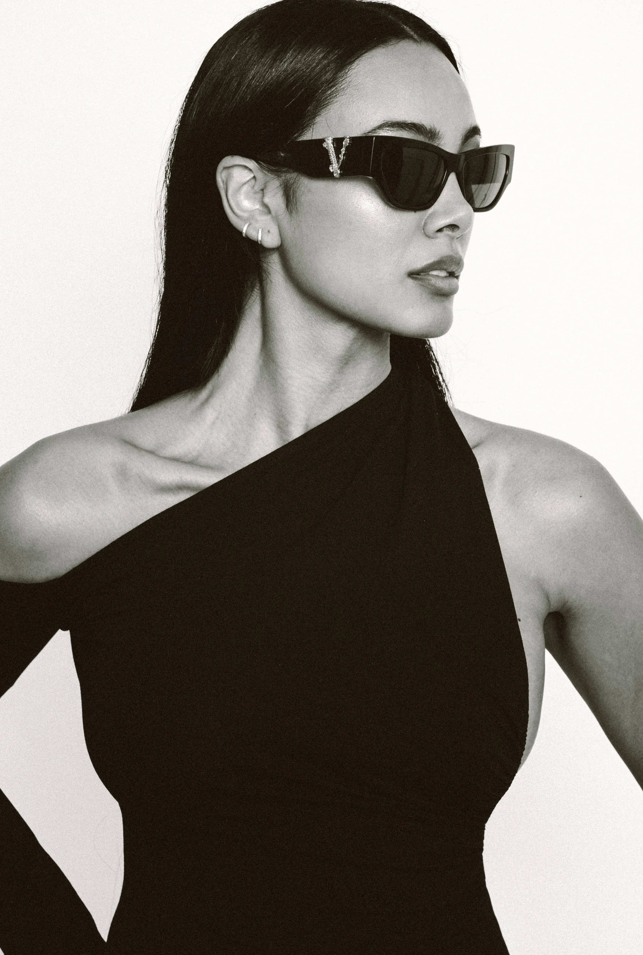 Editorial luxury portrait of Jennifer Elysee wearing designer sunglasses and a black asymmetric dress with sleek straight hair.