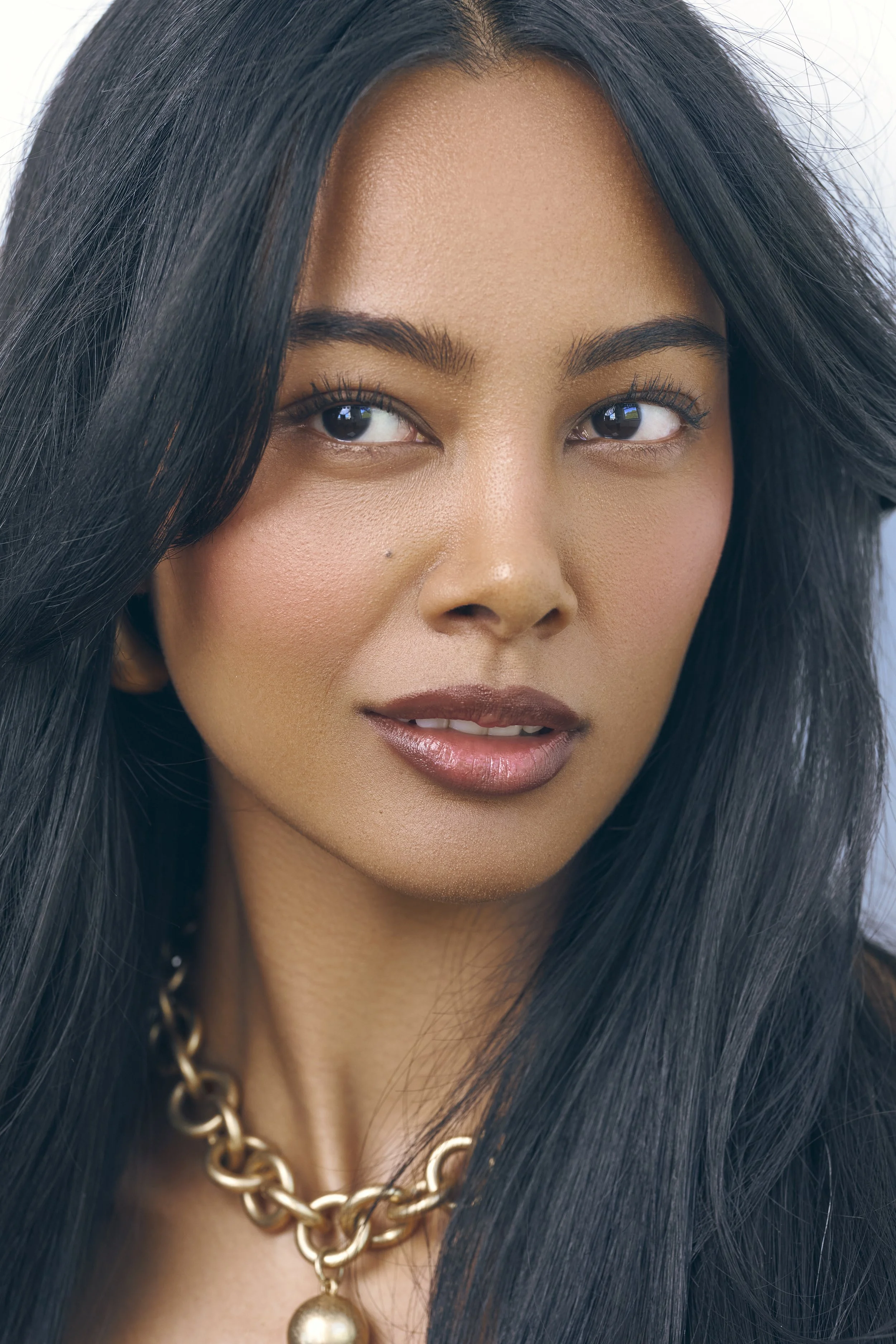 Luxury beauty close-up of Jennifer Elysee featuring natural makeup, glossy lips and long dark hair.
