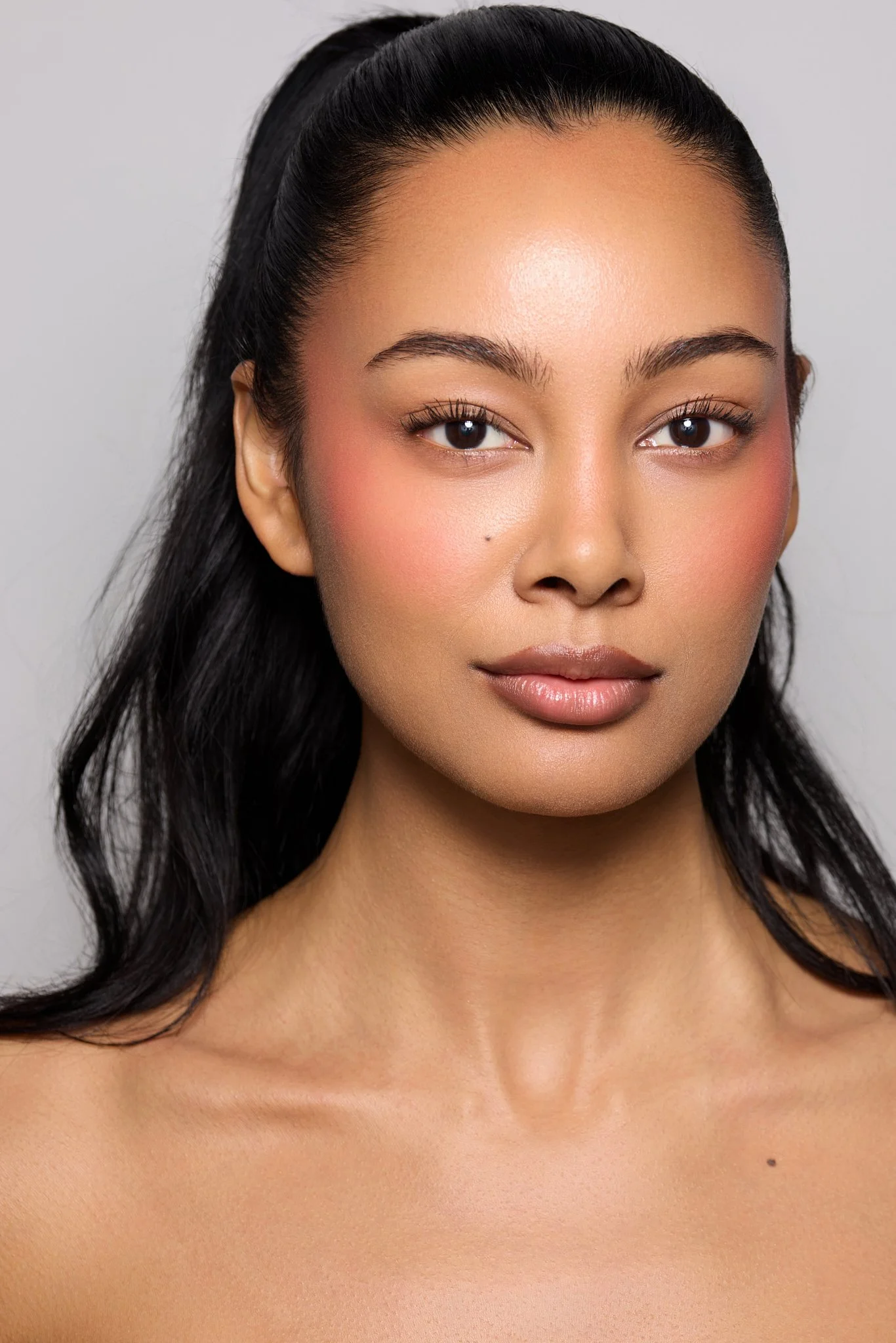 Clean beauty portrait of Jennifer Elysee with a sleek ponytail and natural glowing makeup.