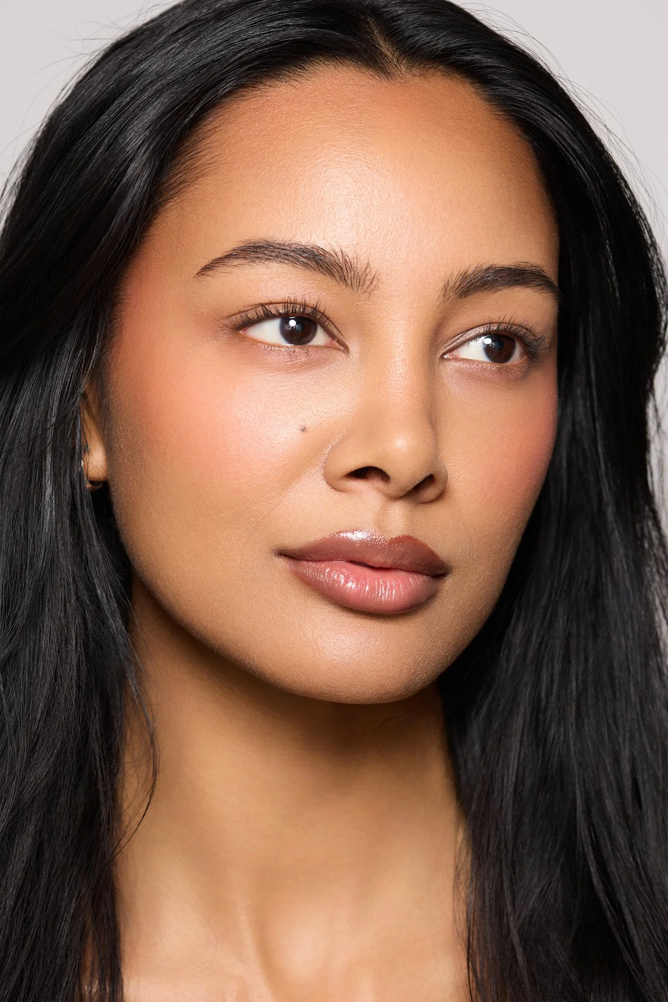 Clean skincare beauty portrait of London model Jennifer Elysee featuring radiant skin and soft natural makeup.