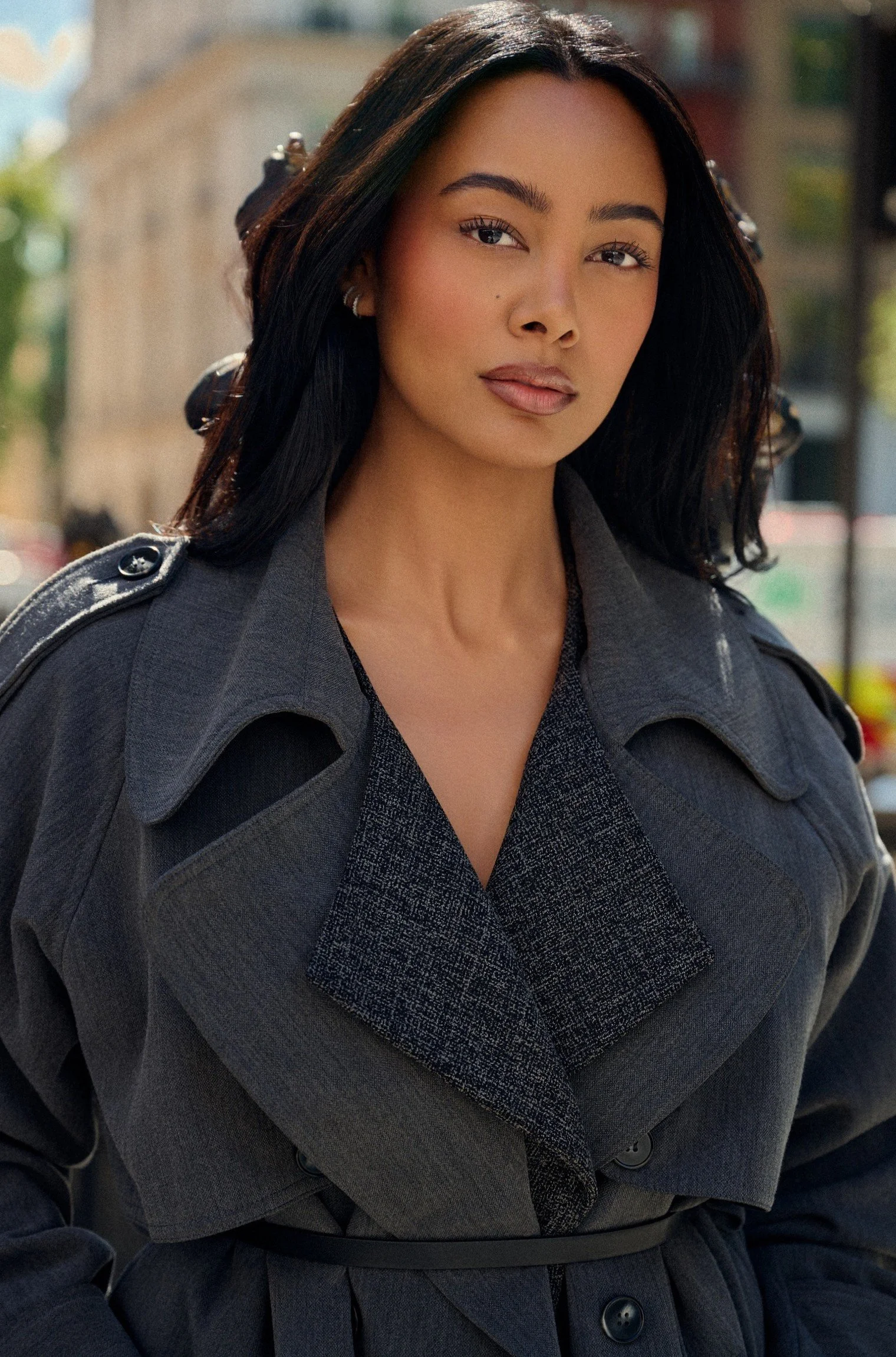 Luxury fashion portrait of commercial model Jennifer Elysee wearing a structured grey trench coat in a London street setting.