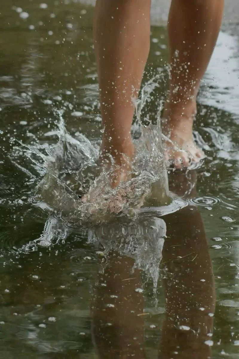 Close-up of a person's feet wading in shallow water, splashing as they walk.