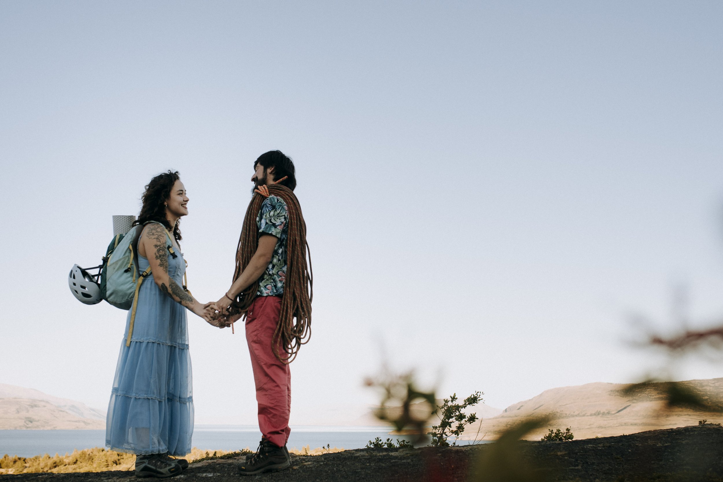 A couple holding hands and smiling at each other outdoors with a scenic landscape during a Patagonia elopement