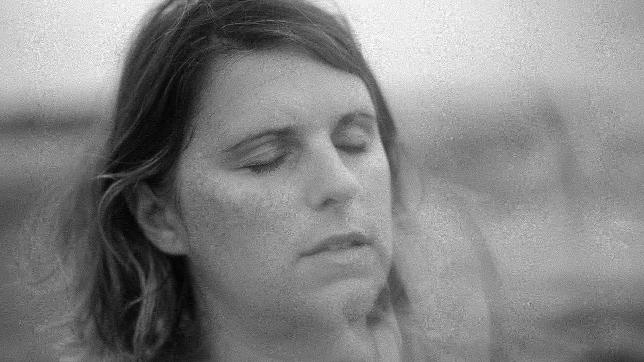Femme aux yeux fermés, cheveux bruns, visage en gros plan.