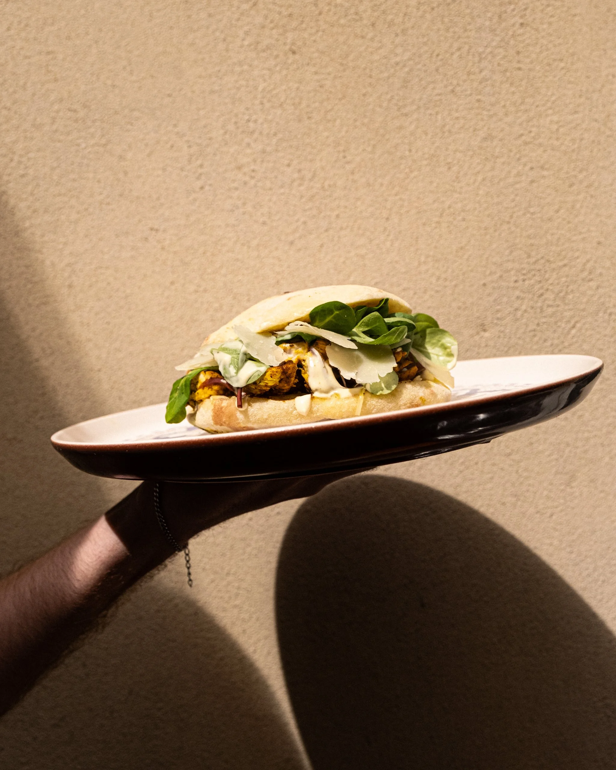 La puccia Riviera disponible chez Giola avec une composition de Aiguillettes de poulet tendres marinées au curry Madras, emmental fermier, crème de moutarde au miel, copaux de Parmigiano Reggiano, pickles d’oignons rouges, mâche nantaise.
