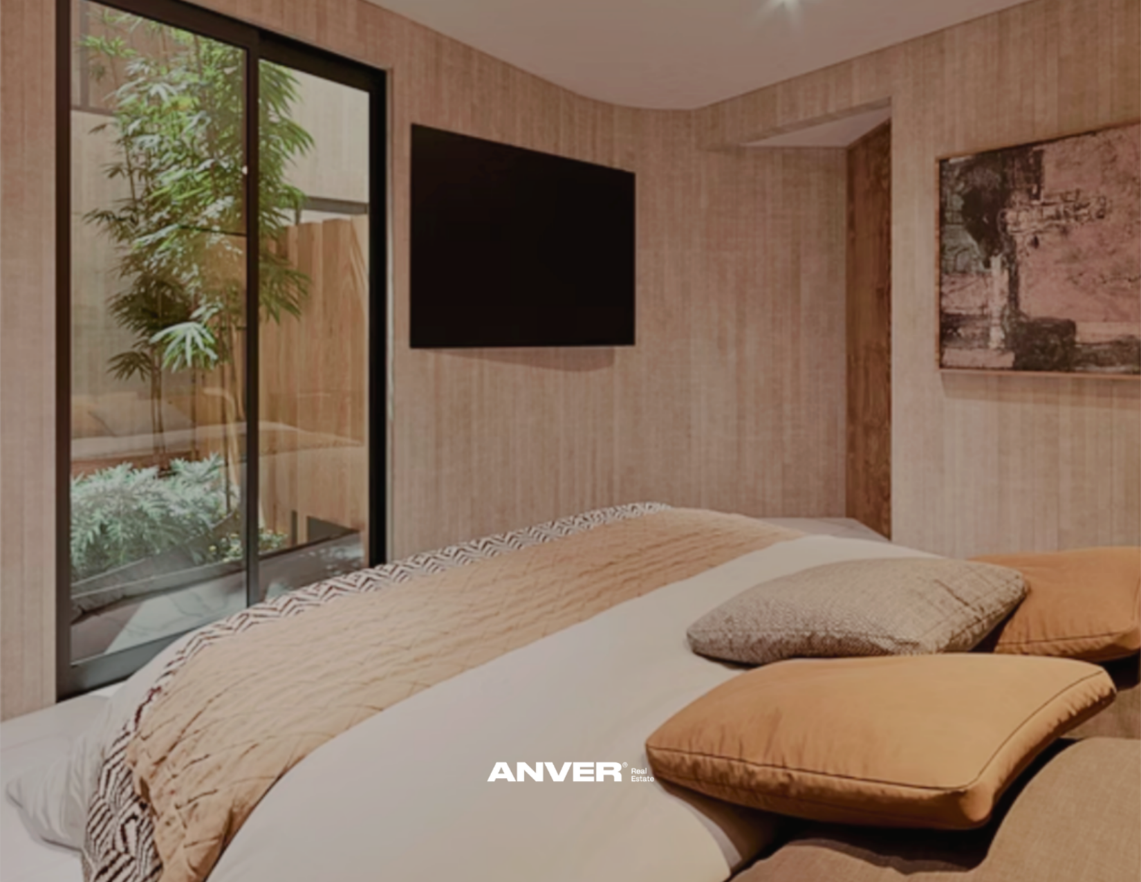 Habitación con ventana corrediza, cama con cobijas beige y almohadas, decoración de paredes en tonos tierra, pantalla de televisión y obra de arte en la pared.