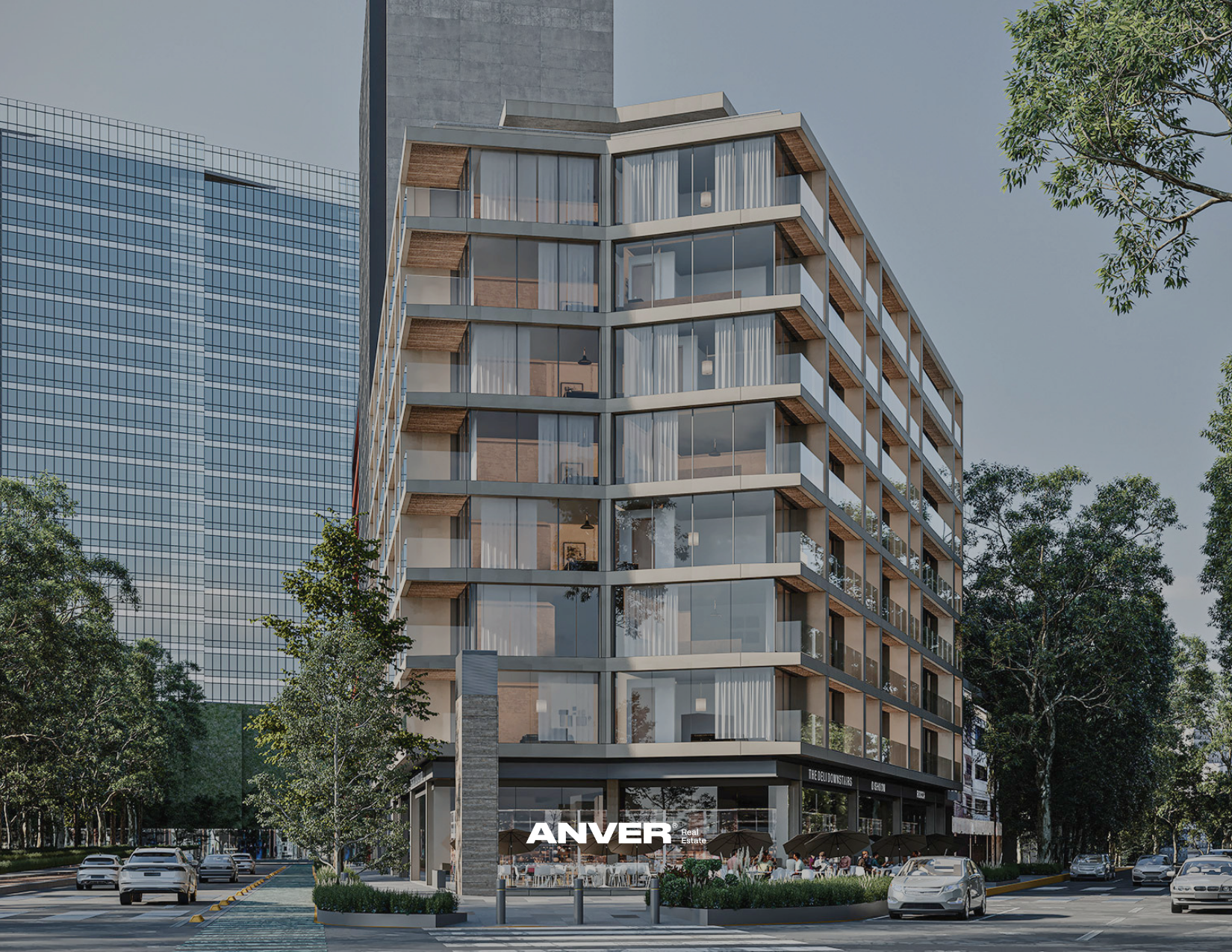 Edificio moderno de varios pisos con fachada de cristal y terrazas, en una calle con árboles y autos estacionados, con el logo 'ANVER' en la parte inferior del edificio.