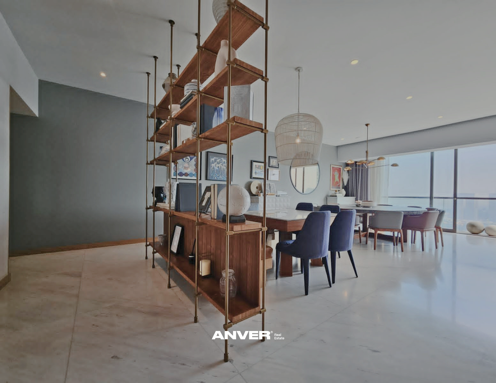 Sala de estar y comedor con gran ventana y decoración moderna, una estantería de madera con productos y libros divide los espacios.