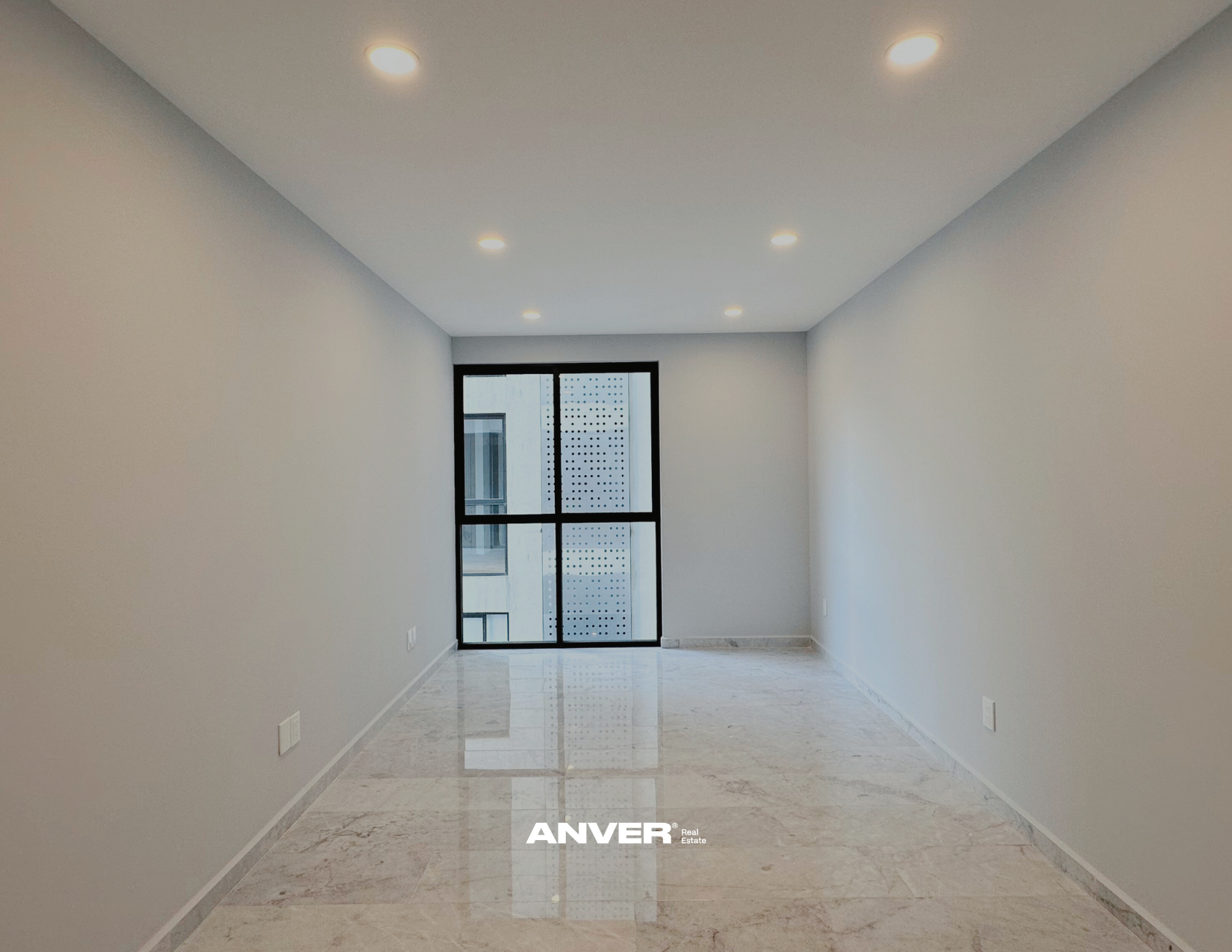 Espacio vacío con paredes blancas, piso de mármol y ventana grande al fondo, en un apartamento moderno.