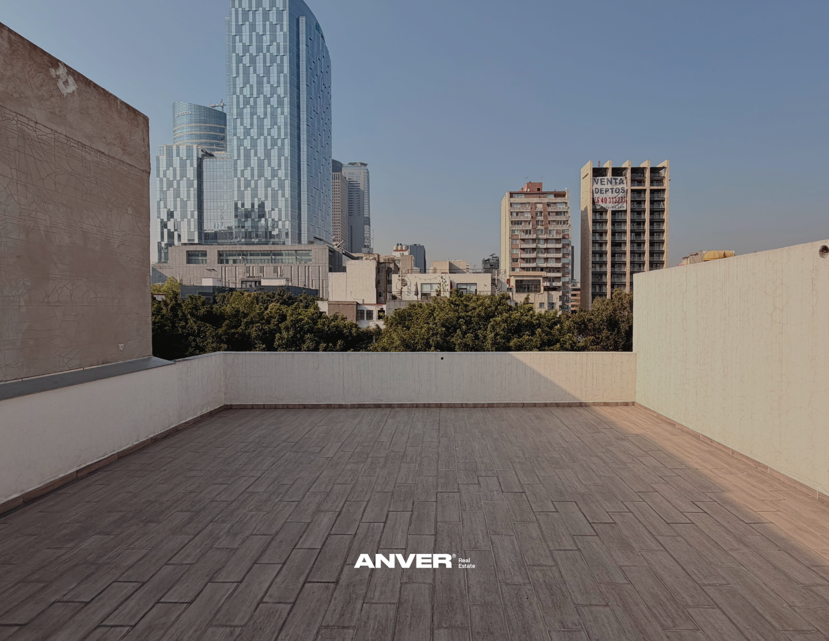Vista de un balcón en la ciudad con edificios modernos y árboles. Texto en la parte inferior que dice 'ANVER'.