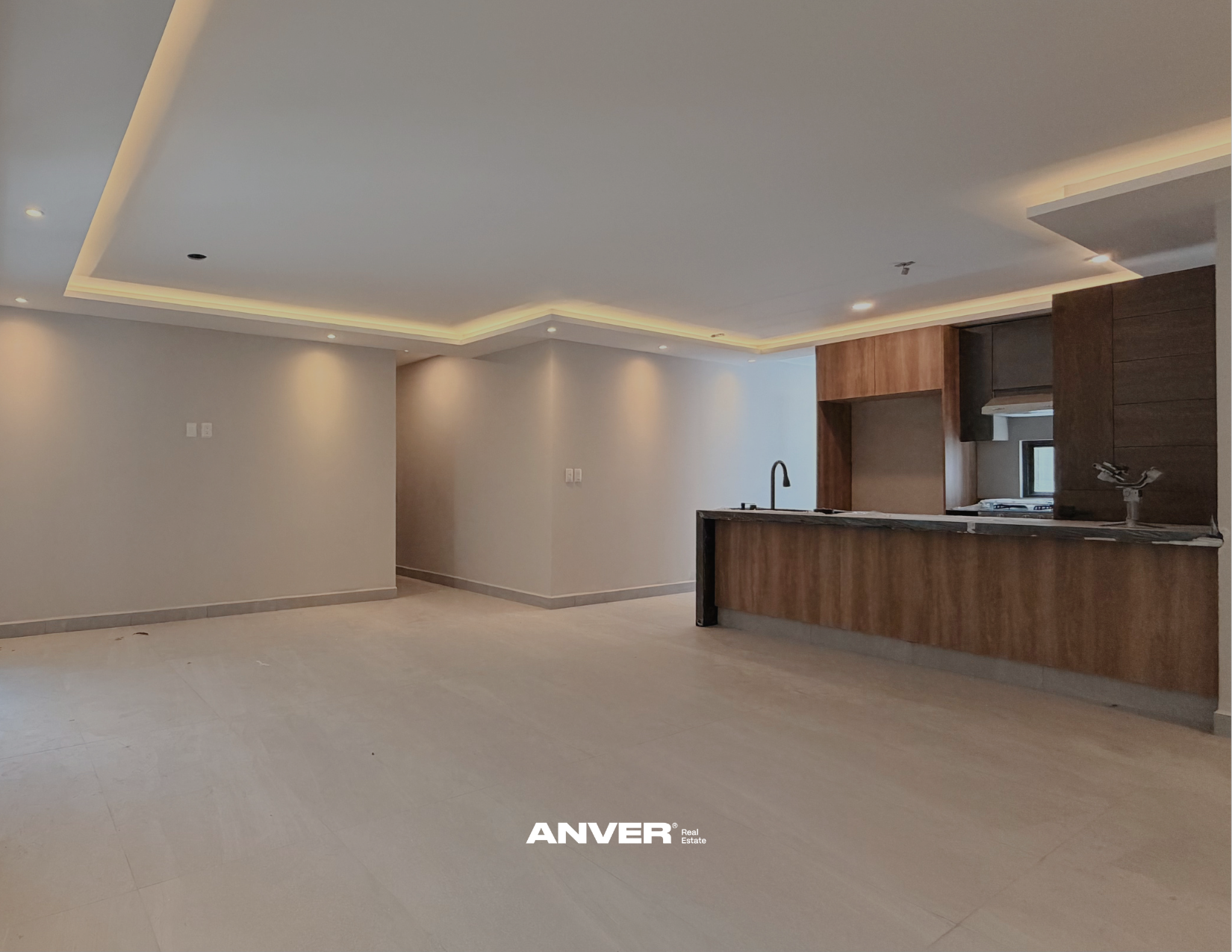 Interiores de una casa moderna con paredes blancas, techo con iluminación empotrada y cocina de madera con isla y lavabo.