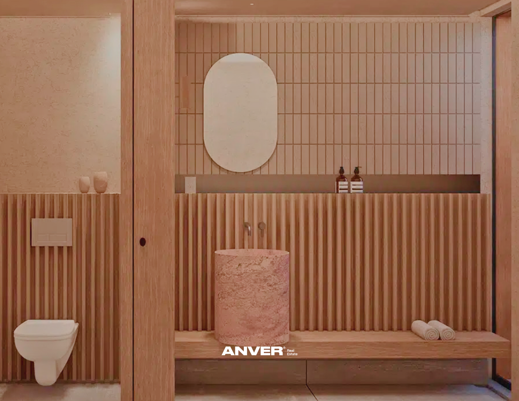 Baño con paredes y mobiliario de madera, inodoro en la esquina izquierda, espejo ovalado en la pared del fondo, dos botellas en una repisa, toallas en el estante inferior, un lavabo de piedra en el centro y objetos decorativos minimalistas.