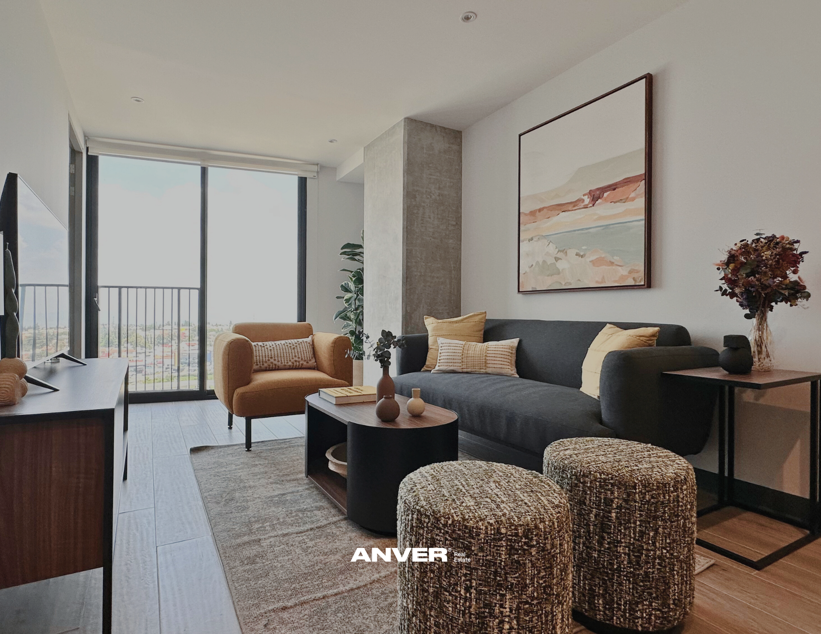 Sala de estar moderna con sillón beige, sofá gris con cojines, mesa de centro oscura con jarrones y libros, cortinas blancas y ventana grande, paredes blancas con cuadro de paisaje y planta verde en la esquina.