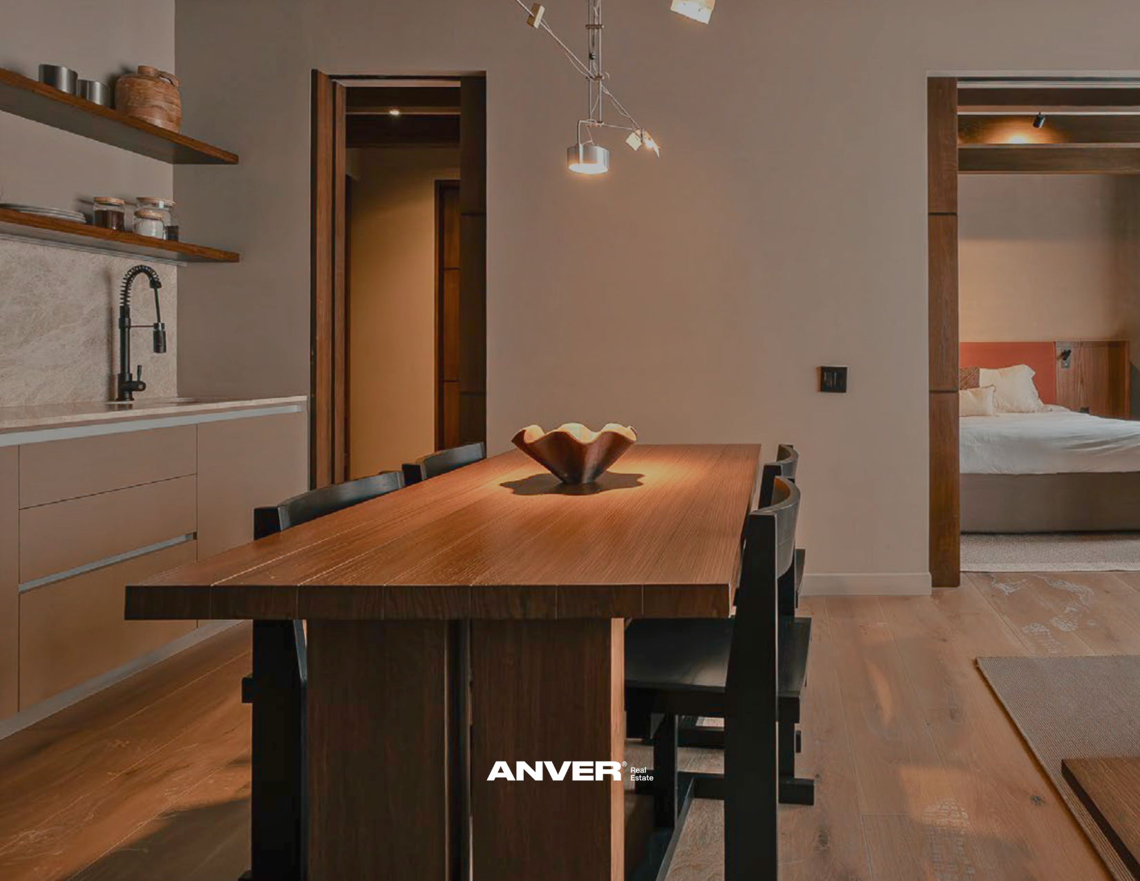 Sala de comedor con mesa de madera y seis sillas negras, cocina en la esquina izquierda, y recámara visible a través de una entrada abierta en la pared del fondo.