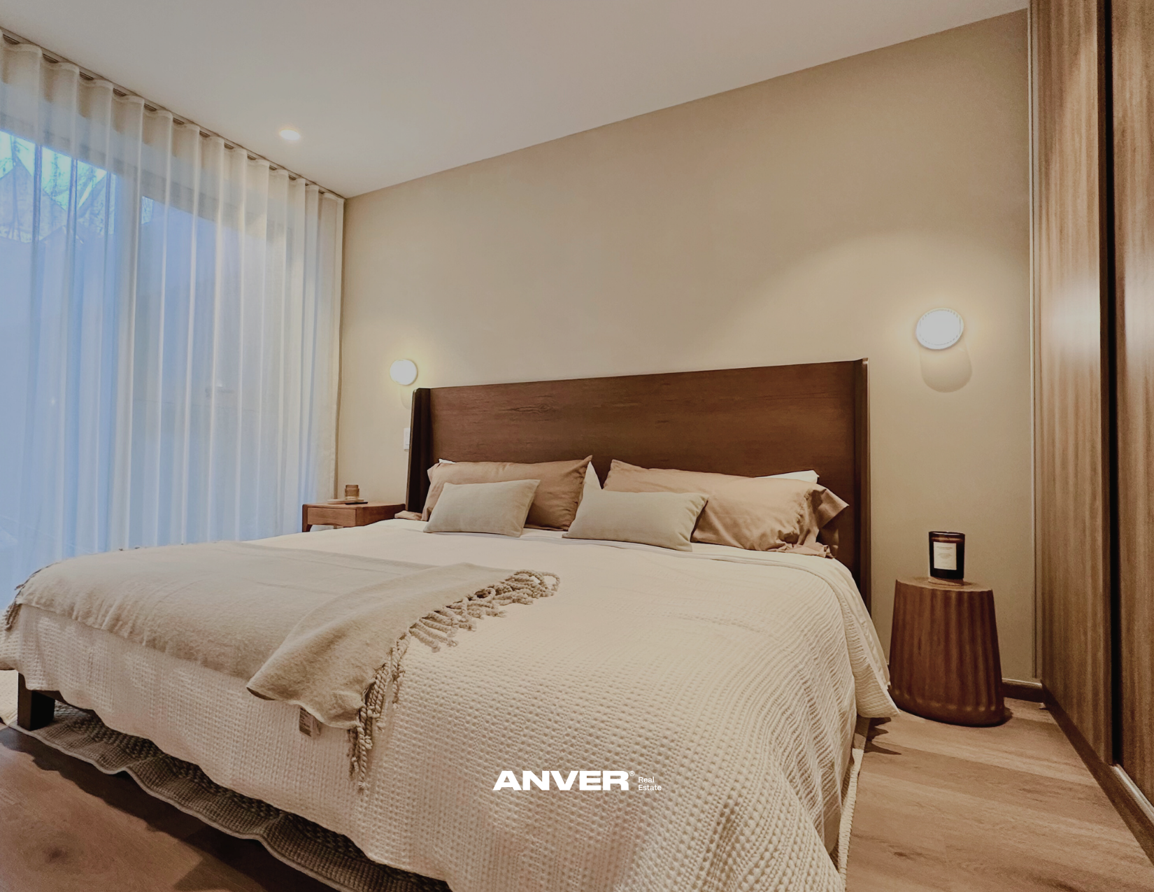 Dormitorio con cama grande, sillones y cortinas blancas.