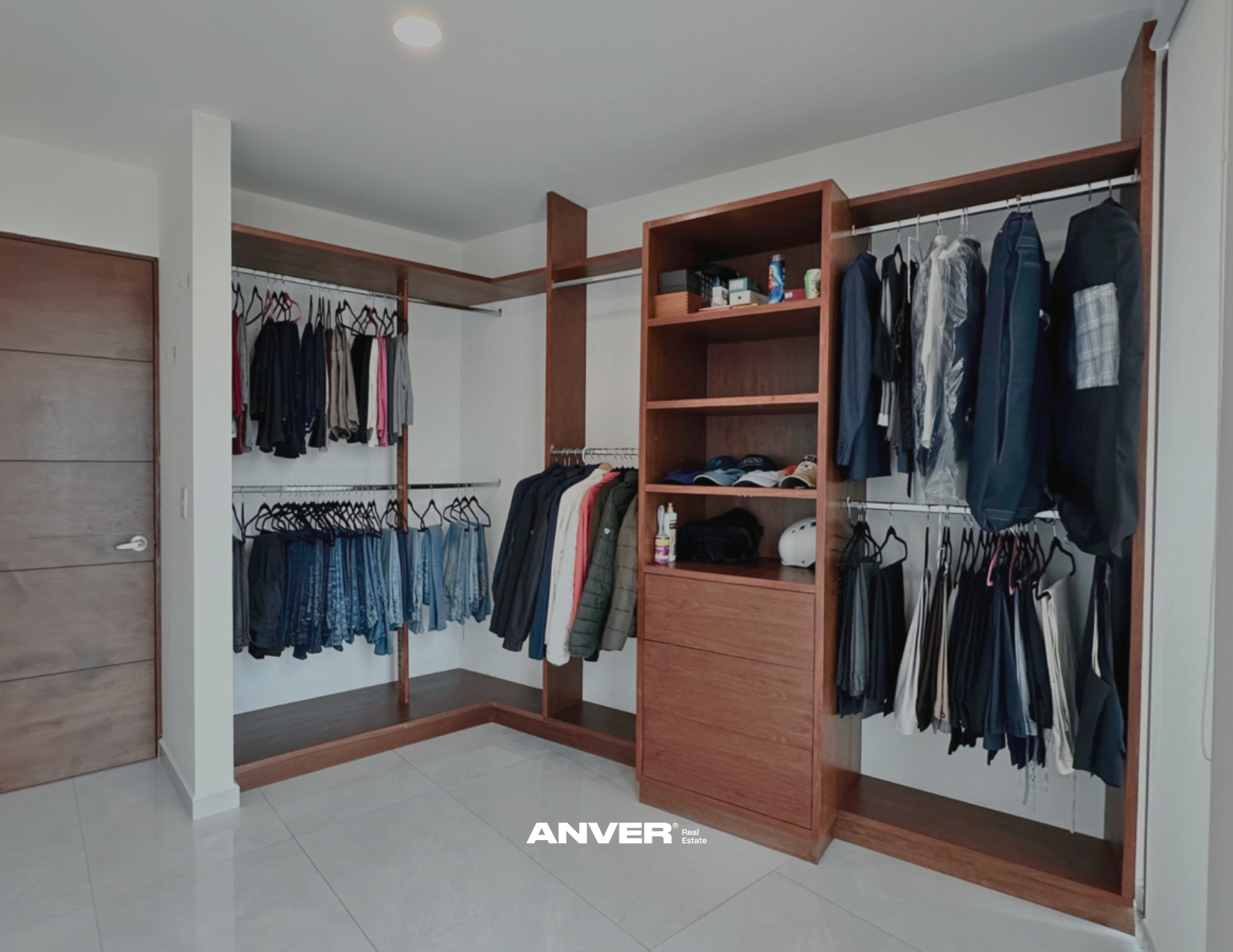 Armario organizado con ropa y accesorios, incluyendo camisas, pantalones, chaquetas, hats y bolsas, en estanterías y barras de colgar.